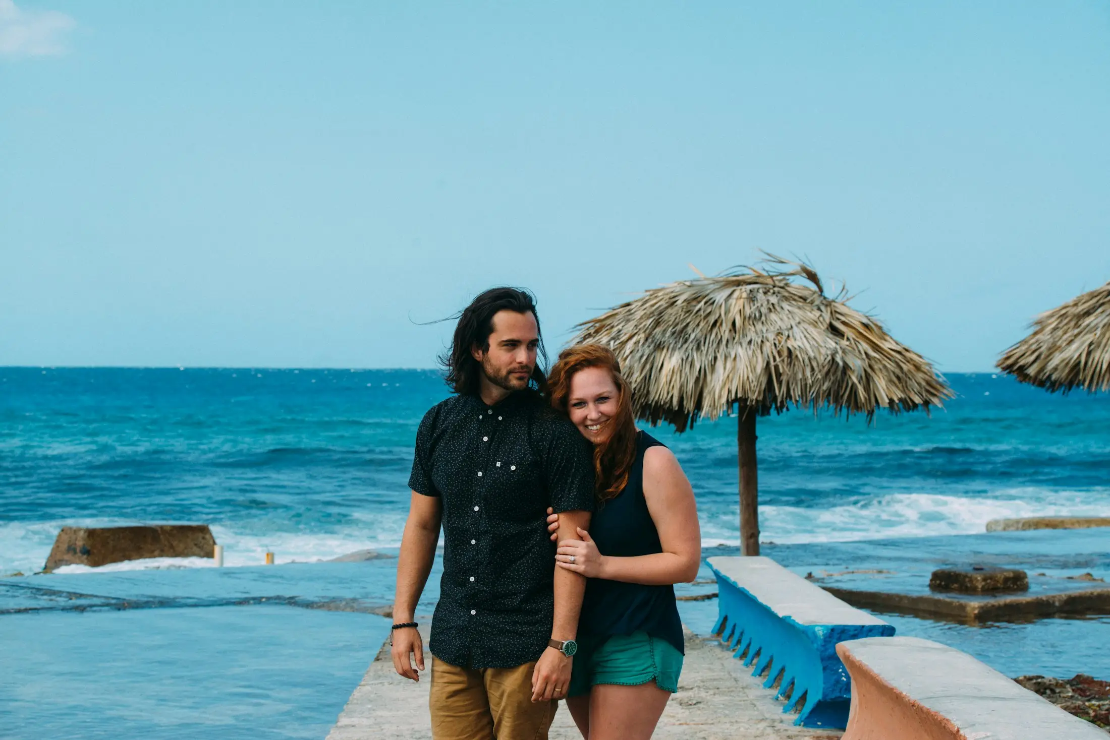 Couple smiling on a jetty over clear tropical water