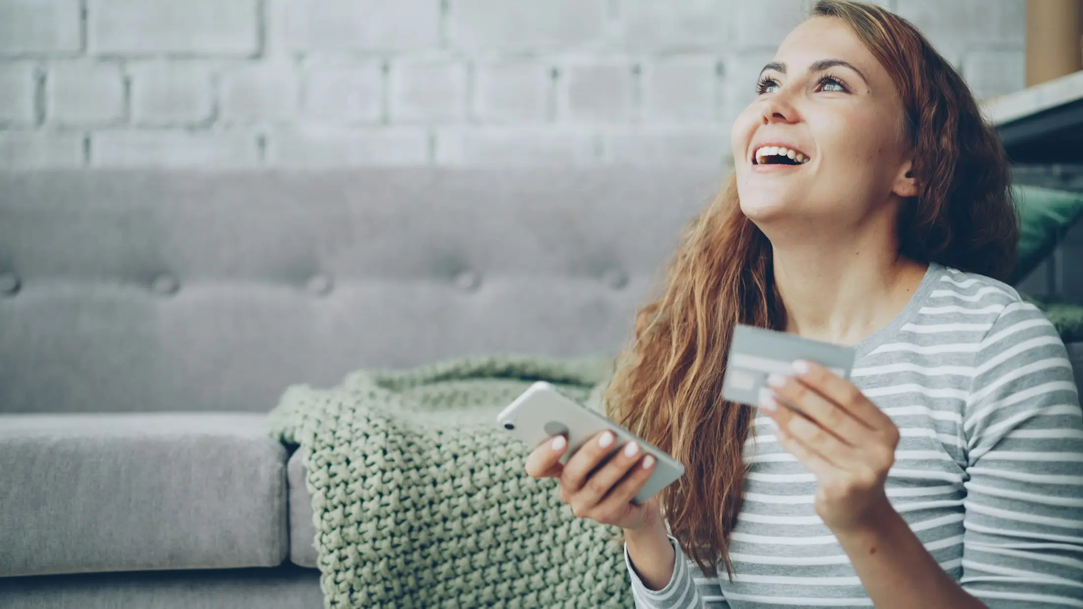 Woman smiling with a bank card and phone