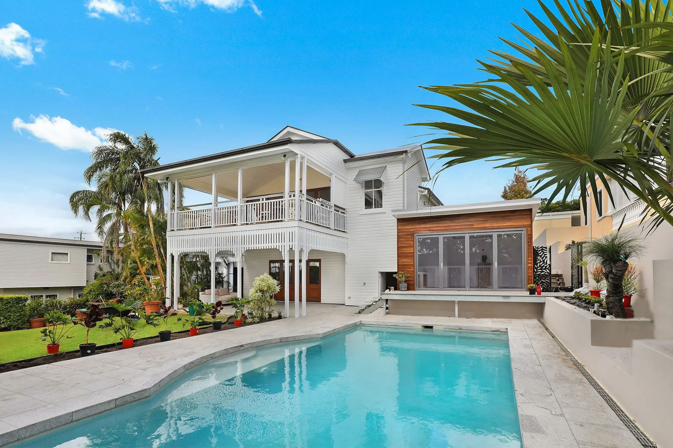 Timber-clad Queenslander-style home with a swimming pool in a leafy garden